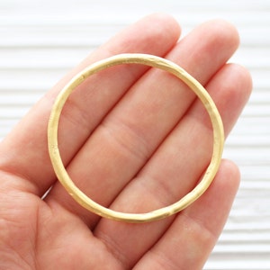 May include: A simple gold bangle bracelet with a smooth, slightly textured finish.