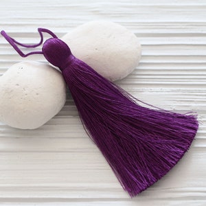 May include: A purple tassel with a long, flowing fringe. The tassel is made of soft, silky material and is perfect for adding a touch of elegance to any project.