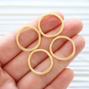 May include: Four gold-colored metal rings of different sizes, displayed on a hand.