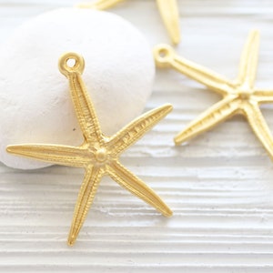 May include: Gold-toned metal starfish charms with a textured surface. The charms have a loop at the top for attaching to jewellery or other crafts.