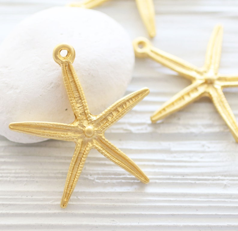 May include: Gold-toned metal starfish charms with a textured surface. The charms have a loop at the top for attaching to jewellery or other crafts.