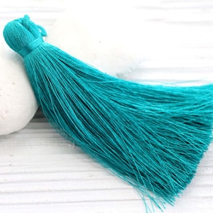 May include: A turquoise blue tassel with a long, flowing fringe. The tassel is made of soft, silky threads and is perfect for adding a touch of elegance to any project.