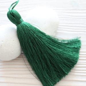 May include: A deep green tassel with a long, flowing fringe. The tassel is made of soft, silky threads and has a simple, elegant design.