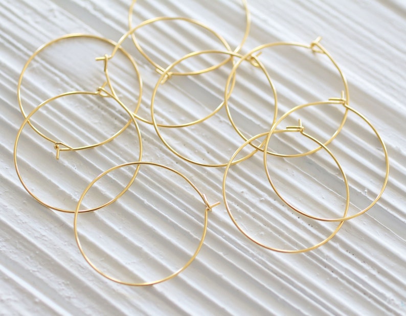 Puede incluir: Un conjunto de ocho pendientes de aro dorados. Los aros son todos del mismo tama&ntilde;o y est&aacute;n dispuestos en un patr&oacute;n aleatorio.