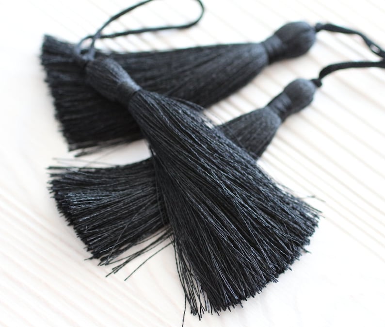 May include: Two black tassel trim pieces with long strands of fringe.