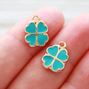 May include: Two gold-coloured four-leaf clover charms with turquoise enamel.