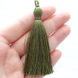May include: A green tassel with a knotted top. The tassel is made of soft, silky threads.