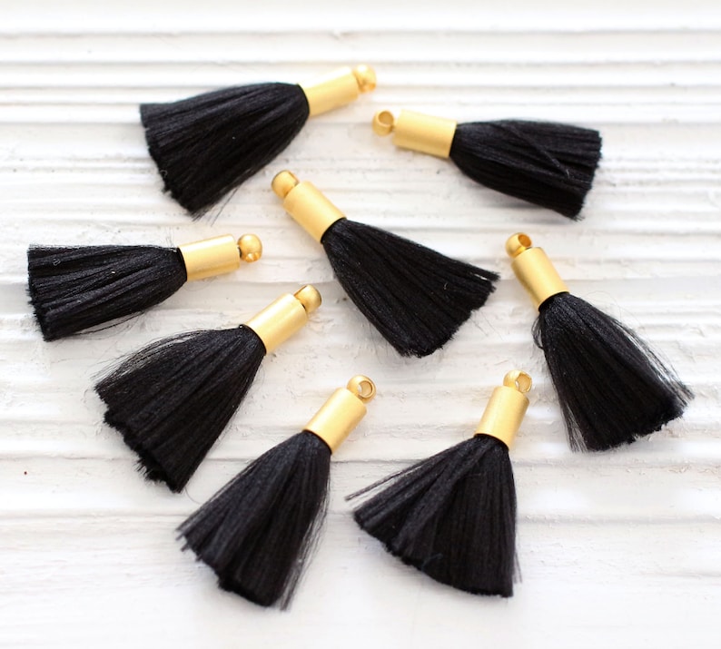 May include: Eight black tassel trim with gold metal caps. The tassels are made of soft, silky fibers and are perfect for adding a touch of elegance to any project.