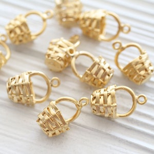 May include: A set of ten gold-toned metal basket charms with a woven design. The charms have a loop at the top for attaching to jewelry or other crafts.