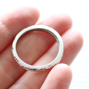 May include: A silver ring with a textured band. The ring is simple and elegant.
