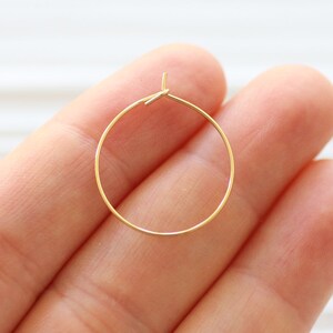 Puede incluir: Aretes de aro de oro con un dise&ntilde;o circular simple. Los aretes est&aacute;n hechos de un alambre delgado y tienen un di&aacute;metro de aproximadamente 2,5 cm.