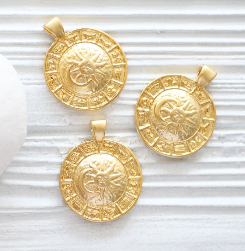 Puede incluir: Tres colgantes de zodiaco dorados con un dise&ntilde;o de sol y luna. Cada colgante presenta los doce signos del zodiaco alrededor del borde.