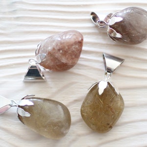May include: Four natural stone pendants with silver bail settings. The stones are various shades of brown and clear with gold flecks.