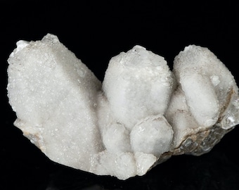 May include: A cluster of white quartz crystals with a rough, natural texture. The crystals are clustered together in a random formation, creating a unique and interesting display.