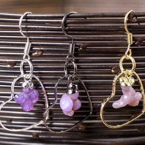 May include: Three pairs of heart-shaped earrings with purple gemstone accents. The earrings are made of silver, gold, and silver with a gold accent.