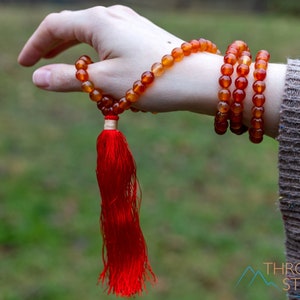 These red orange Carnelian necklaces have 108 sphere beads with a red tassel.  
Crystals are nature-made therefore each one is unique in appearance.