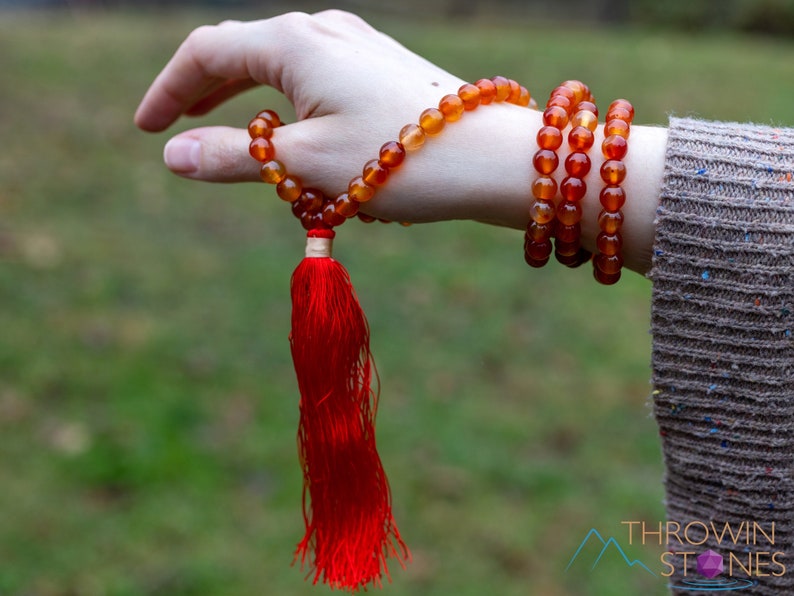 These red orange Carnelian necklaces have 108 sphere beads with a red tassel.  
Crystals are nature-made therefore each one is unique in appearance.