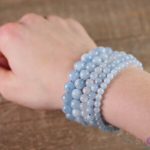 Handcrafted Aquamarine round beaded bracelet. These polished, blue beads are drilled and strung on elastic cord. Each crystal bracelet is unique in shape, color, and pattern and has a wrist circumference of about 6 to 7 inches. Listing has variations