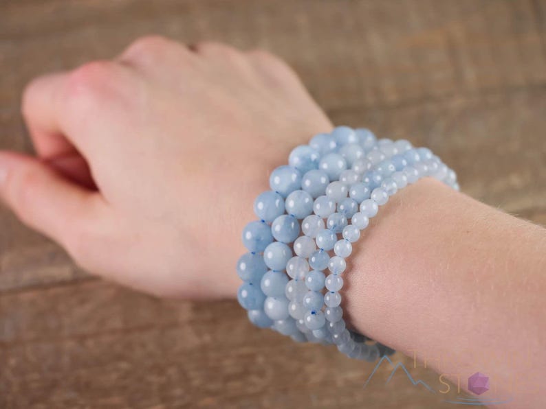 Handcrafted Aquamarine round beaded bracelet. These polished, blue beads are drilled and strung on elastic cord. Each crystal bracelet is unique in shape, color, and pattern and has a wrist circumference of about 6 to 7 inches. Listing has variations