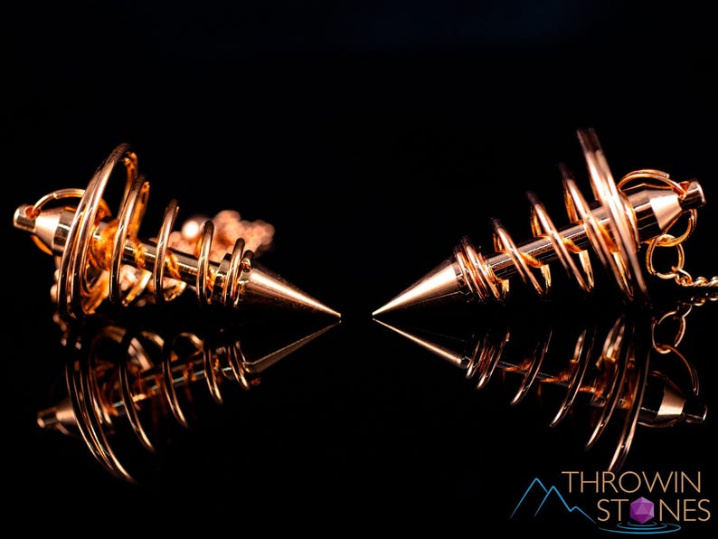 These copper pendulums are wire spirals with a pointed tip, with a copper chain and bead.