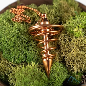 These copper pendulums are wire spirals with a pointed tip, with a copper chain and bead.