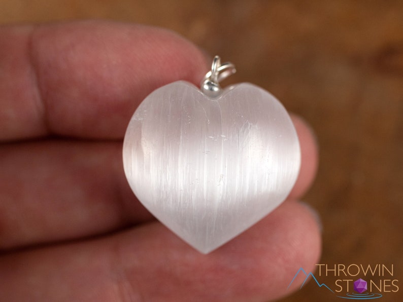These chatoyant white Selenite crystal pendants are heart shaped, with a silver bail. 
Crystals are nature-made therefore each one is unique in appearance.