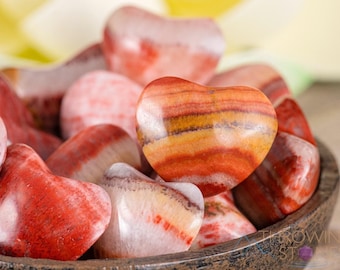 May include: A bowl filled with heart-shaped red, orange, and white striped stones. The stones are polished and have a smooth, glossy finish.