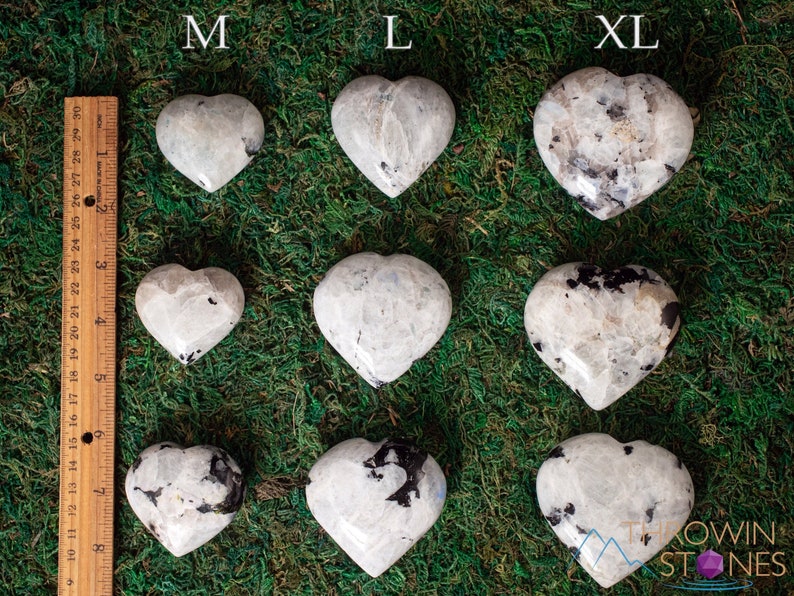 Genuine Moonstone heart shaped crystal. This beautifully hand carved, puffy, palm stone heart, is white with specks of black and rainbow flash. Each crystal heart is unique, and has its own color, shape, and pattern. This listing has variations.