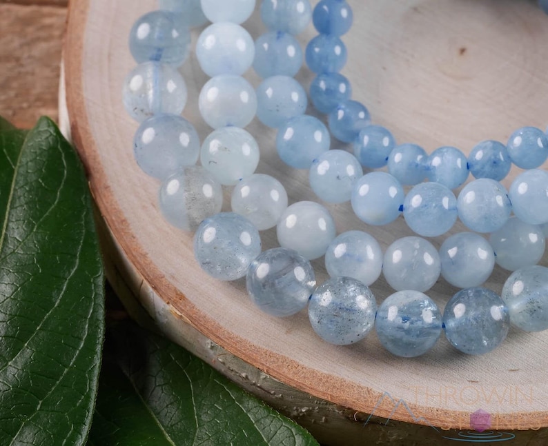 Handcrafted Aquamarine round beaded bracelet. These polished, blue beads are drilled and strung on elastic cord. Each crystal bracelet is unique in shape, color, and pattern and has a wrist circumference of about 6 to 7 inches. Listing has variations