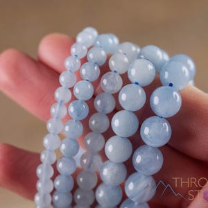 Handcrafted Aquamarine round beaded bracelet. These polished, blue beads are drilled and strung on elastic cord. Each crystal bracelet is unique in shape, color, and pattern and has a wrist circumference of about 6 to 7 inches. Listing has variations