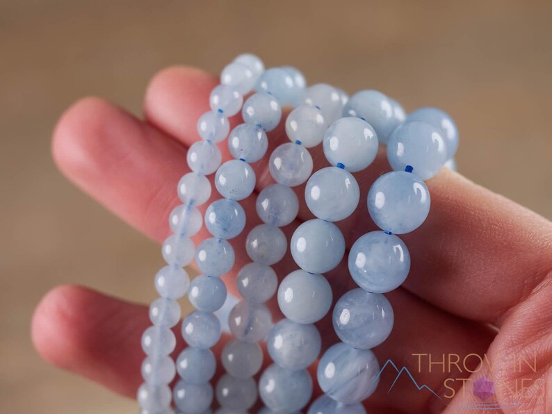 Handcrafted Aquamarine round beaded bracelet. These polished, blue beads are drilled and strung on elastic cord. Each crystal bracelet is unique in shape, color, and pattern and has a wrist circumference of about 6 to 7 inches. Listing has variations