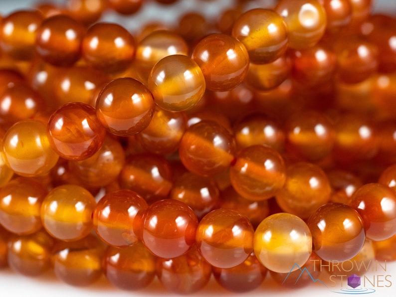 These red orange Carnelian necklaces have 108 sphere beads with a red tassel.  
Crystals are nature-made therefore each one is unique in appearance.