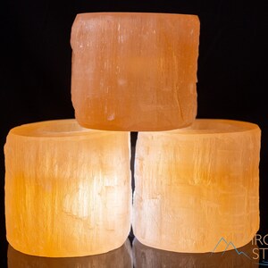 These peachy orange Selenite crystal carved raw cylindrical votive candle holders range in a variety of sizes.  
Crystals are nature-made therefore each one is unique in appearance.