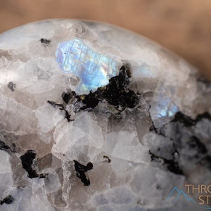 Genuine Moonstone heart shaped crystal. This beautifully hand carved, puffy, palm stone heart, is white with specks of black and rainbow flash. Each crystal heart is unique, and has its own color, shape, and pattern. This listing has variations.