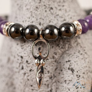 These purple Amethyst and grey Hematite crystal bracelets have round beads strung on elastic.  They feature a silver Goddess Charm.
Crystals are nature-made therefore each one is unique in appearance.