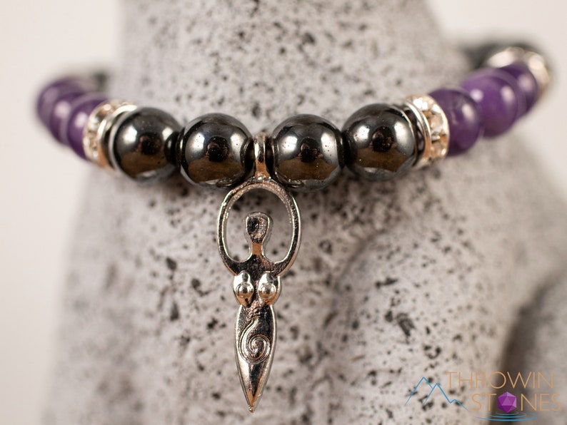 These purple Amethyst and grey Hematite crystal bracelets have round beads strung on elastic.  They feature a silver Goddess Charm.
Crystals are nature-made therefore each one is unique in appearance.