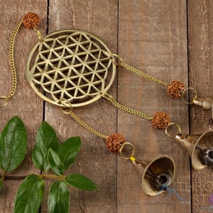 These are small brass wind chimes in the shape of a disc with the "flower of life" sacred geometry design, with bells and Rudraksha beads.