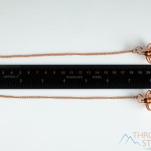 These copper pendulums are wire spirals with a pointed tip, with a copper chain and bead.