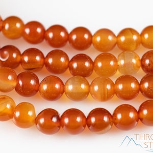 These red orange Carnelian necklaces have 108 sphere beads with a red tassel.  
Crystals are nature-made therefore each one is unique in appearance.