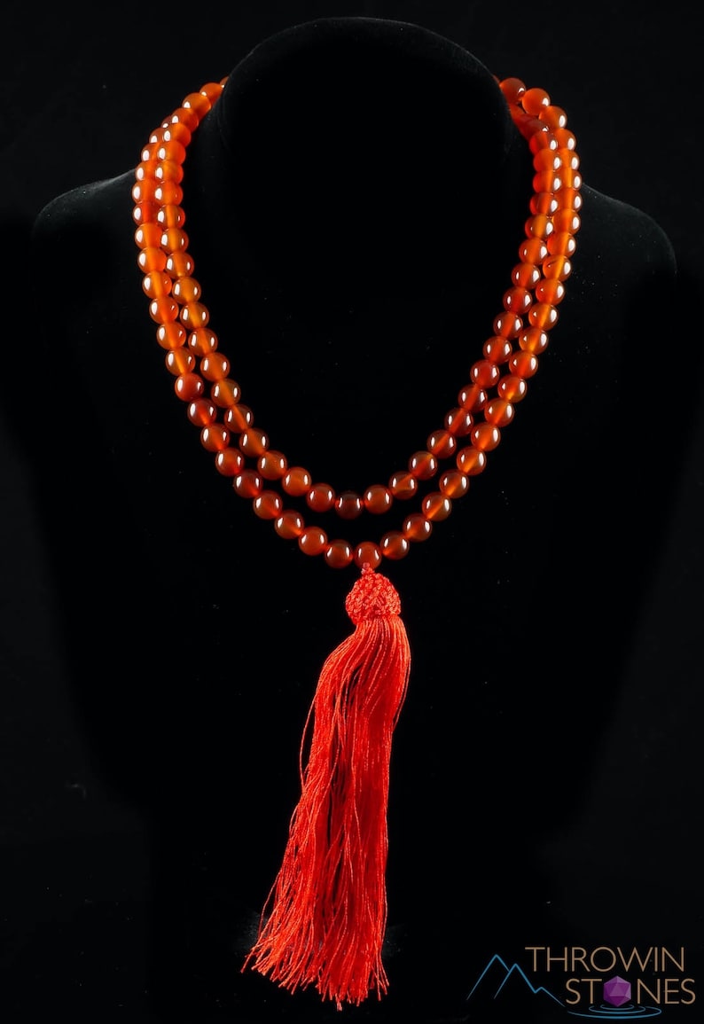 These red orange Carnelian necklaces have 108 sphere beads with a red tassel.  
Crystals are nature-made therefore each one is unique in appearance.