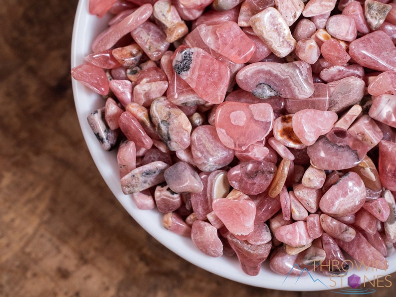 Rhodochrosite Crystal Chips. These stones are light pink to bright pink and often include a white banding. They are great for jewelry making and crystal decor. Each specimen is unique and varies in color, shape, and pattern. Listing has variations.