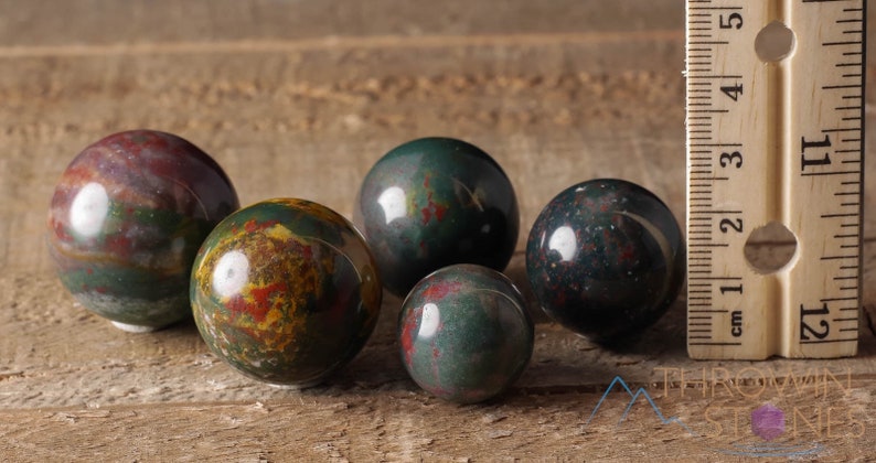 Natural Bloodstone crystal sphere, with wooden stand. This semi-precious, crystal ball is green with red hematite inclusions. Each crystal sphere is beautifully handcrafted, ethically sourced and comes with a wooden stand. This Listing has variations