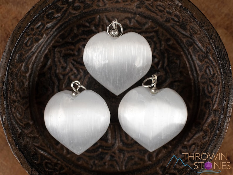These chatoyant white Selenite crystal pendants are heart shaped, with a silver bail. 
Crystals are nature-made therefore each one is unique in appearance.
