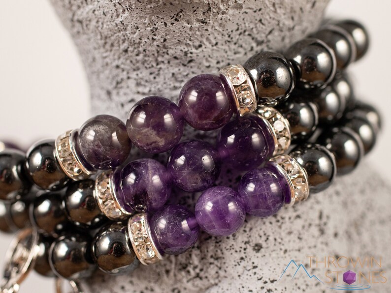These purple Amethyst and grey Hematite crystal bracelets have round beads strung on elastic.  They feature a silver Goddess Charm.
Crystals are nature-made therefore each one is unique in appearance.
