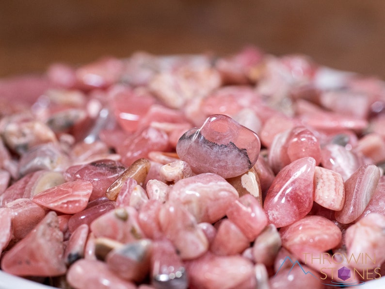 Rhodochrosite Crystal Chips. These stones are light pink to bright pink and often include a white banding. They are great for jewelry making and crystal decor. Each specimen is unique and varies in color, shape, and pattern. Listing has variations.