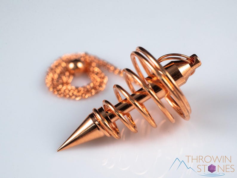 These copper pendulums are wire spirals with a pointed tip, with a copper chain and bead.