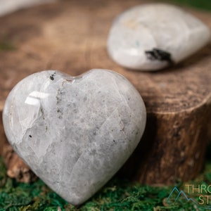 Genuine Moonstone heart shaped crystal. This beautifully hand carved, puffy, palm stone heart, is white with specks of black and rainbow flash. Each crystal heart is unique, and has its own color, shape, and pattern. This listing has variations.