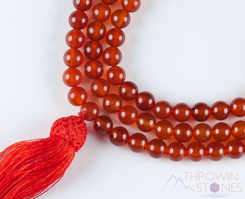 These red orange Carnelian necklaces have 108 sphere beads with a red tassel.  
Crystals are nature-made therefore each one is unique in appearance.