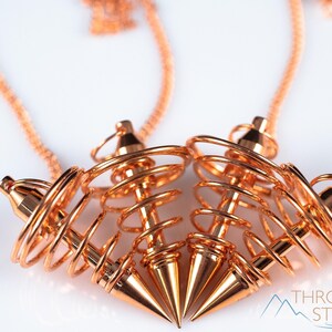 These copper pendulums are wire spirals with a pointed tip, with a copper chain and bead.
