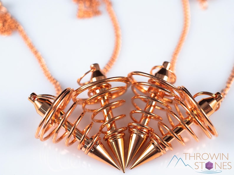 These copper pendulums are wire spirals with a pointed tip, with a copper chain and bead.